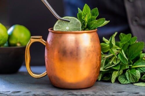 A Moscow Mule Cocktail in a traditional copper cup, with lime and mint garnish - The Ultimate Moscow Mule Recipe