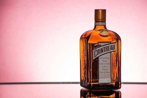 A picture of a Cointreau bottle cast against a pink background for the What is Triple Sec article.