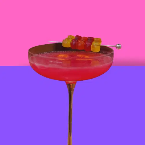 Pink Red Apple cocktail in a coupe with a fruit skewer