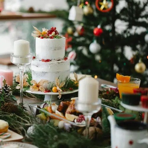 Festive table with a Christmas cake, candles and a decorated tree